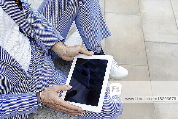 Hands of businessman holding tablet PC sitting on bench