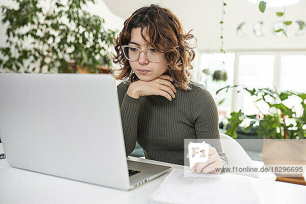 Freelancer using laptop sitting on table at home