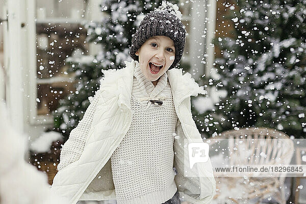Happy boy having fun in snow at front yard