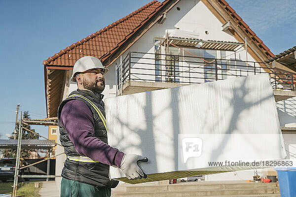 Construction worker holding polystyrene foam in front of house