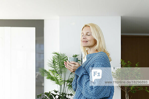Smiling woman holding tea cup at home