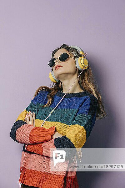 Girl listening music through headphones against purple background