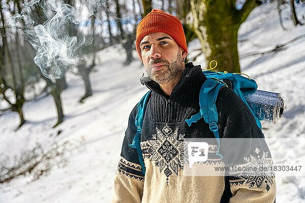 Porträt eines Mannes  der auf einem verschneiten Hügel im Winter eine Zigarette raucht