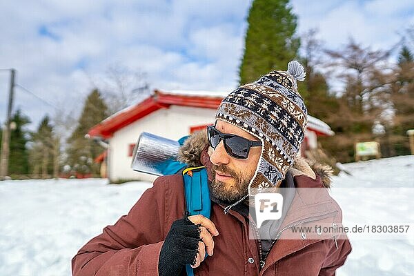 Mann trinkt im Winter im Schnee Kaffee aus einer heißen Thermoskanne  bevor er zum Trekking aufbricht
