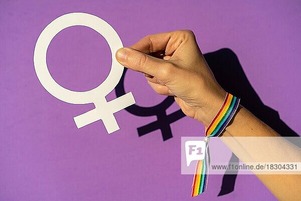Eine Frau hält ein weibliches Symbol Zeichnung  lila Hintergrund  kämpfen zugunsten der Frauen  weibliche Stärke  LGTB Flagge