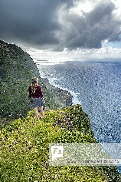 Junge Frau genießt Ausblick auf Steilküste mit Klippen und Meer  Küstenlandschaft  Aussichtspunkt Ponta da Leideira  bei Calhau das Achadas  Madeira  Portugal  Europa