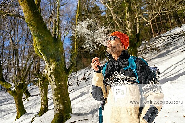 Ein Mann raucht eine Zigarette auf einem verschneiten Hügel im Winter