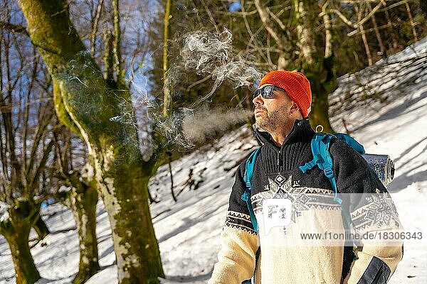 A man smoking a cigarette on a snowy hill in winter  enjoying the cold smoking