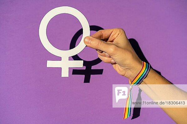 Eine Frau hält ein weibliches Symbol Zeichnung  lila Hintergrund  kämpfen zugunsten der Frauen  weibliche Stärke  LGTB Flagge