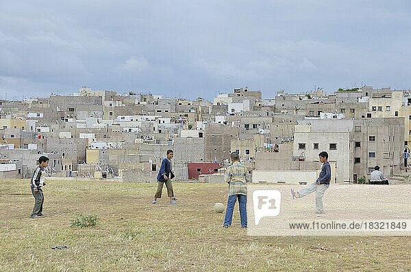 Jungs spielen Fußball  dahinter Häuser und Wohnungen der ärmeren Bevölkerung  Siedlung außerhalb von Fes  Marokko  Afrika