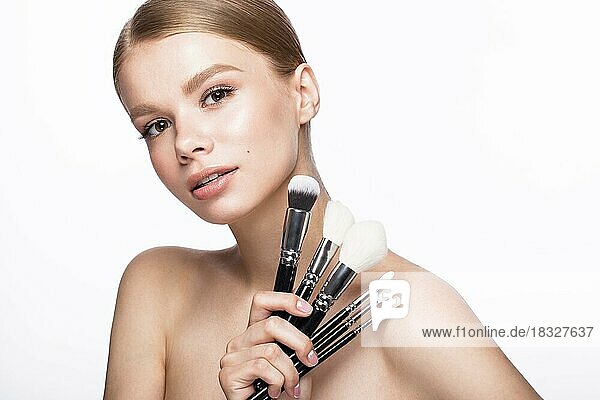 Beautiful young girl with a light natural make-up  brushes for cosmetics and French manicure. Beauty face. Picture taken in the studio on a white background