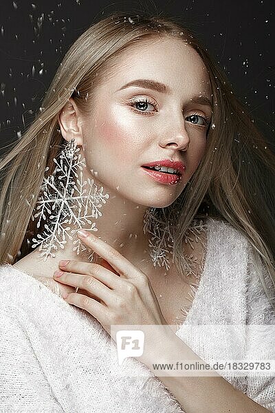 Schönes blondes Mädchen in einem Winterbild mit Schnee. Schönes Gesicht. Foto im Studio aufgenommen