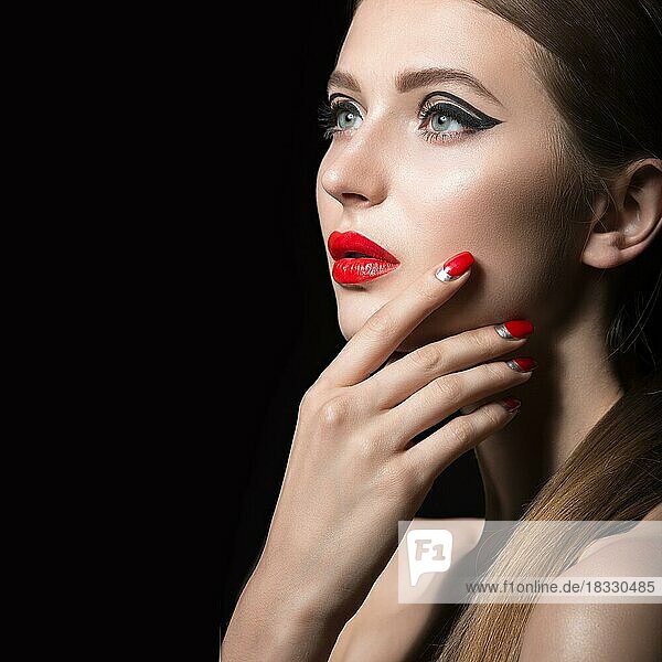 Schönes junges Mädchen mit einem hellen Make-up und roten Nägeln. Bild im Studio auf einem schwarzen Hintergrund aufgenommen