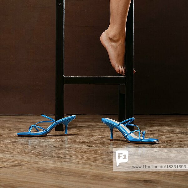 Blaue Sandalen mit Absätzen auf dem Boden neben dem Stuhl (Fokus auf Schuhe)