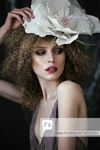 Schönes Mädchen mit lockigem Haar in Dessous mit großer Blume. Die Schönheit des Gesichts. Fotos im Studio geschossen