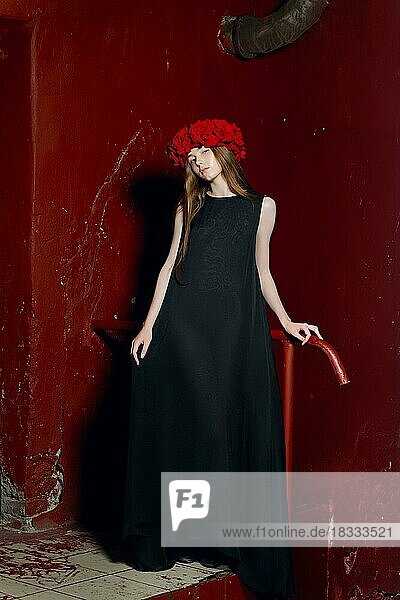 Modemodell in langem Designerkleid und Blumenkranz auf dem Kopf bei Nacht