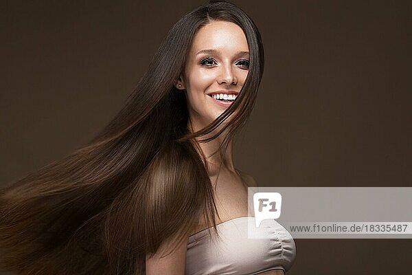 Beautiful brunette girl in move with a perfectly smooth hair  and classic make-up. Beauty face. Picture taken in the studio