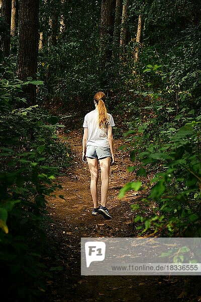 Eine junge Frau wandert auf einem Waldweg