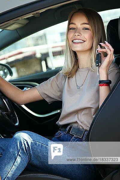 Glücklich lächelndes Mädchen in einem neuen Auto mit Schlüssel in der Hand. Lebensstil