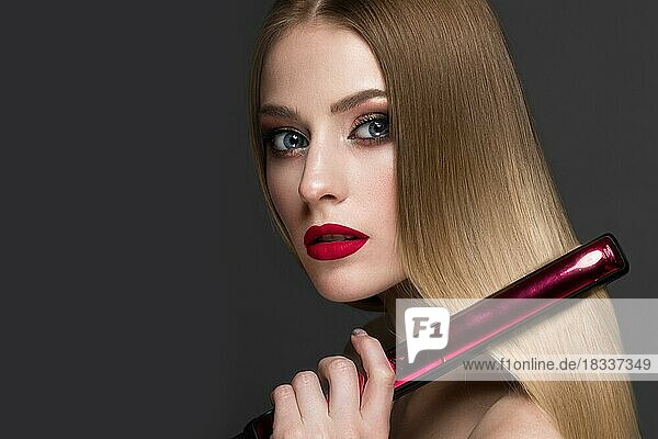 Beautiful blond girl with a perfectly smooth hair  curling  classic make-up and red lips. Beauty face. Picture taken in the studio on a white background