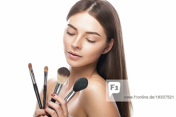 Beautiful young girl with a light natural make-up  brushes for cosmetics and perfect skin. Beauty face. Picture taken in the studio on a white background