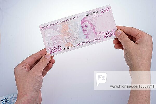Hand hält türkische Lira-Banknote auf weißem Hintergrund