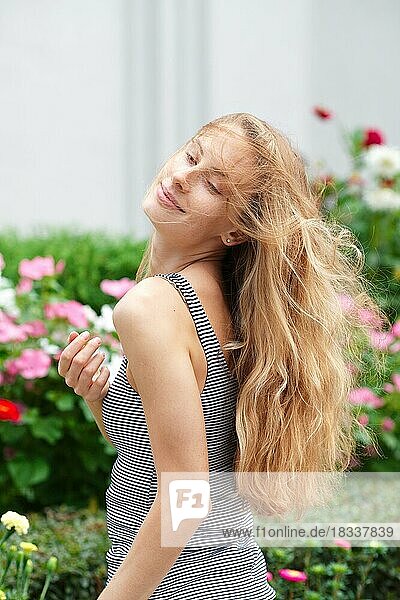 Nettes Mädchen  das durch den Blumengarten spaziert. Glückliche Touristin mit Wind in ihrem Haar