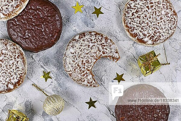 Deutscher runder Lebkuchen mit weißer und Schokoladenglasur und fehlendem Biss  umgeben von weihnachtlicher Dekoration