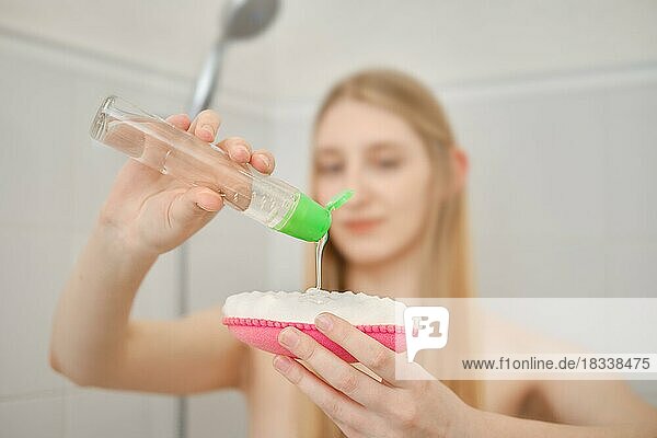 Frau drückt Duschgel auf einem Waschlappen aus (Fokus auf Hände) (geringe Tiefenschärfe)
