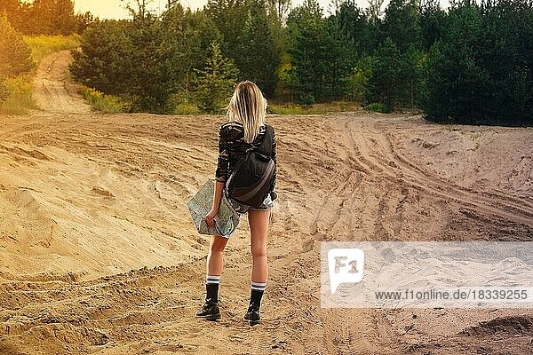 Rückseite eines reisenden Mädchens auf der Suche nach der richtigen Richtung auf einer Karte am Waldrand