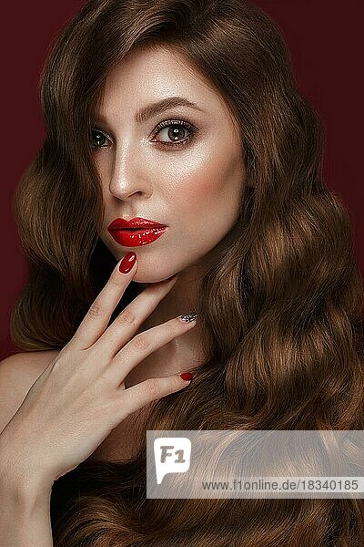 Schönes Mädchen mit einem klassischen Make-up  Locken Haar und rote Nägel. Maniküre Design. Schönes Gesicht. Foto im Studio aufgenommen