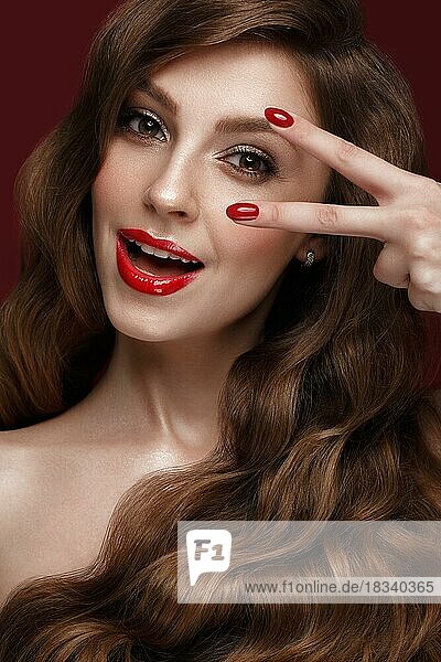 Schönes Mädchen mit einem klassischen Make-up  Locken Haar und rote Nägel. Maniküre Design. Schönes Gesicht. Foto im Studio aufgenommen