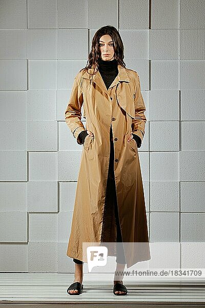 Full length portrait of ttractive girl in long raincoat