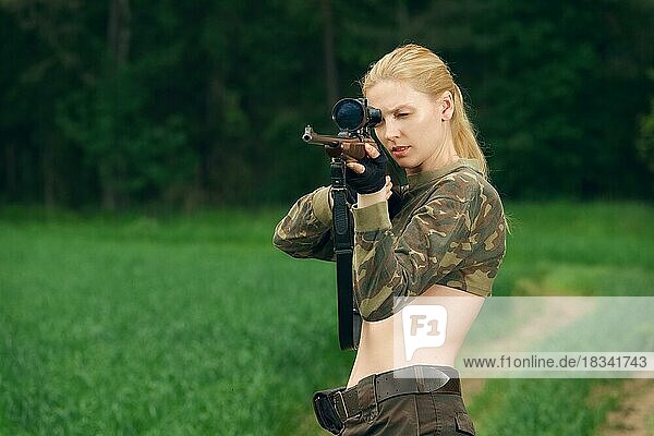 Hübsches Jägermädchen  das mit einem Jagdgewehr im Wald zielt. Karabiner mit optischem Visier