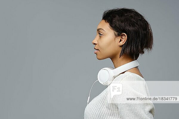 Closeup-Porträt einer afrikanischen Frau mit Kopfhörern im Nacken im Profil stehend. Foto mit Kopierraum