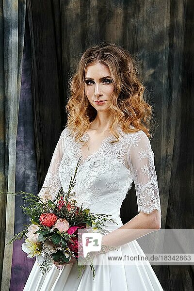 Porträt einer hübschen Braut im Hochzeitskleid mit Blumen in der Hand
