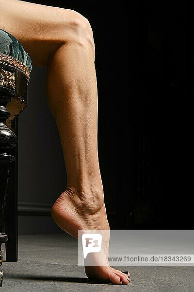 Low-Key-Foto eines barfuß gehenden Frauenbeins auf Zehenspitzen