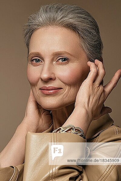 Porträt einer schönen älteren Frau in einem beigen Regenmantel mit klassischem Make-up und grauem Haar