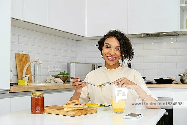 Lächelnde afrikanisch-amerikanische Frau beim traditionellen Frühstück mit Spiegelei und frischem Gemüse zu Hause