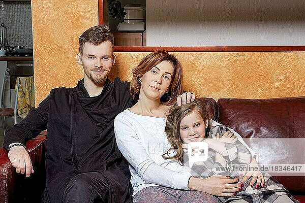 Porträt einer glücklichen Familie  die sich auf dem Sofa sitzend umarmt