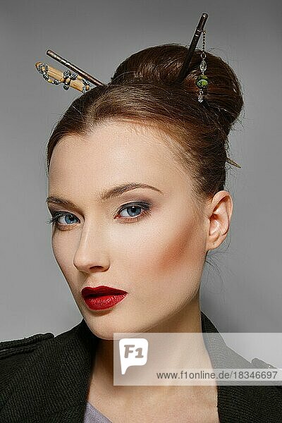 Porträt eines Models mit orientalischer Frisur  roten Lippen und blauen Augen. Perfekte gesunde Haut