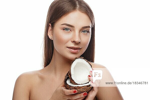 Schönes junges Mädchen mit einem leichten natürlichen Make-up und perfekter Haut mit Kokosnuss in der Hand. Schönes Gesicht. Bild im Studio auf einem weißen Hintergrund aufgenommen