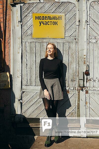 Pretty model posing in front of factory door with warning plate. (inscription on plate is on Russian can be translated as model area)