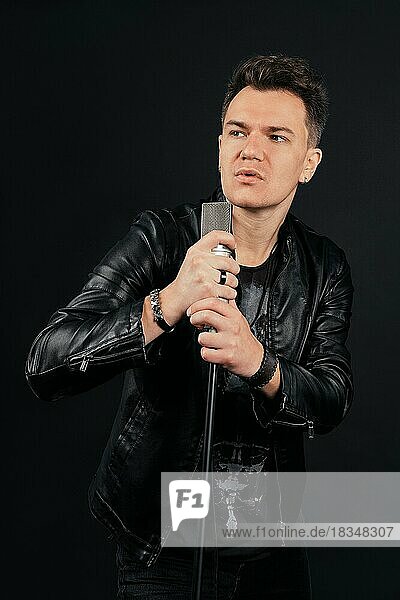 Low key portrait of man singing and holding microphone