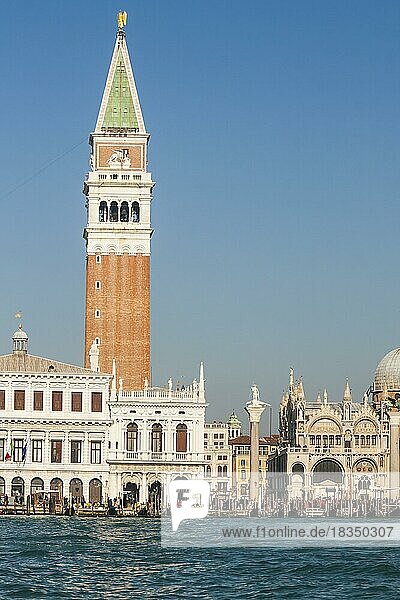 Blick auf den Markusplatz vom Wasser aus mit dem Markus-Turm  einem Teil des Markusdoms  der Bibliothek und der Säule von St. Theodor  Touristen auf der Uferpromenade und Gondeln auf dem Wasser  Venedig  Italien  Europa