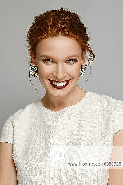 Smiling fashion model with red mat lips and gemstone earrings. perfect skin  natural make up