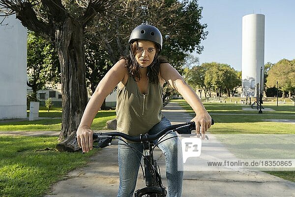 Frau fährt mit dem Fahrrad im Park in Richtung der Kamera