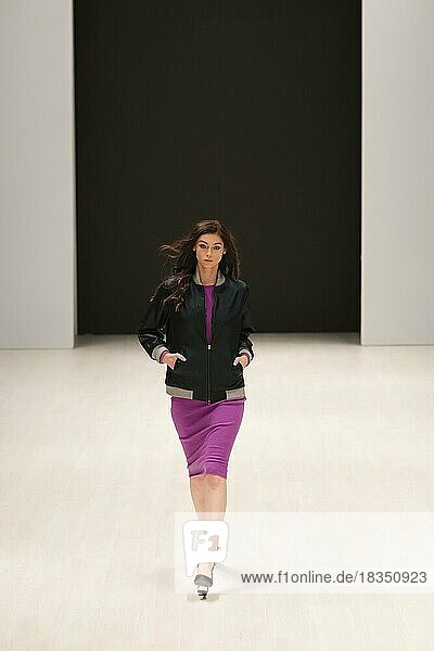 Modemodell läuft auf dem Laufsteg in einem Strickkleid und einer Clubjacke während der Fashion Week Show