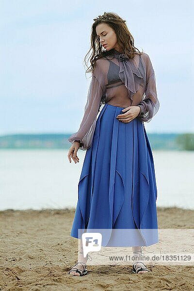 Sanftes und mystisches Foto einer jungen Frau in blauem Rock und transparenter Bluse