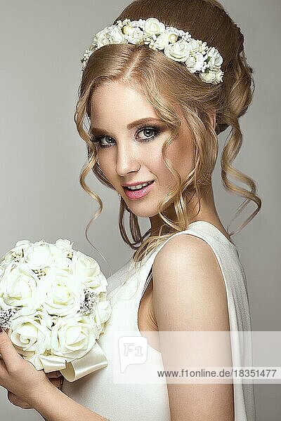 Porträt eines schönen blonden Mädchens im Bild der Braut mit weißen Blumen auf dem Kopf. Schönheit Gesicht. Foto im Studio auf einem grauen Hintergrund geschossen